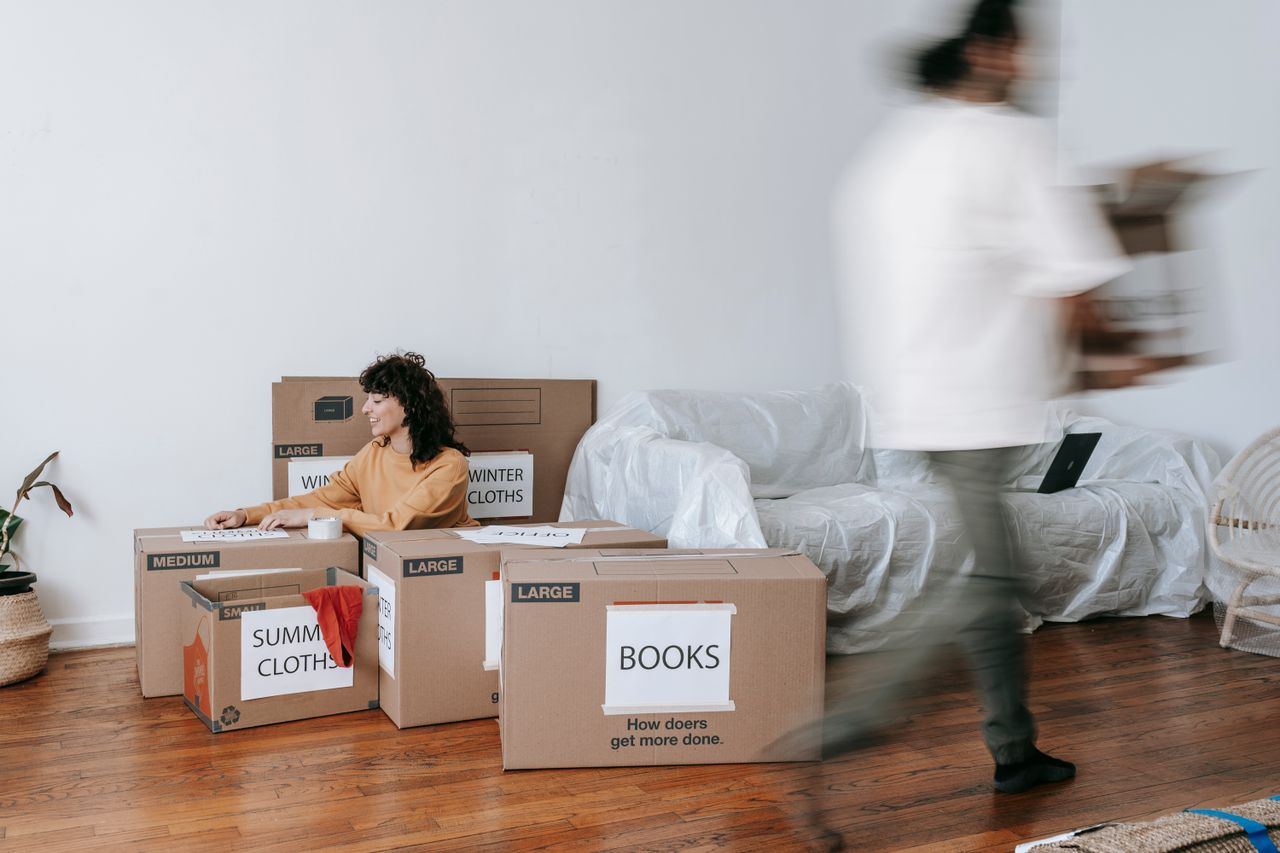 Un couple range des cartons étiquetés dans un salon au style minimaliste, en vue du jour du déménagement.